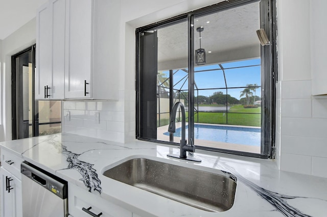 kitchen featuring white cabinets, light stone countertops, dishwasher, and sink