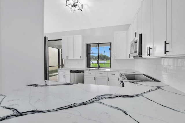 kitchen featuring decorative backsplash, light stone counters, white cabinetry, and appliances with stainless steel finishes