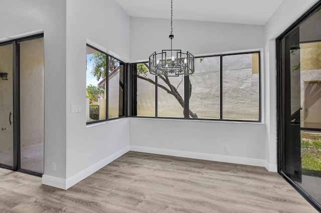 unfurnished dining area featuring light hardwood / wood-style flooring, plenty of natural light, and a notable chandelier