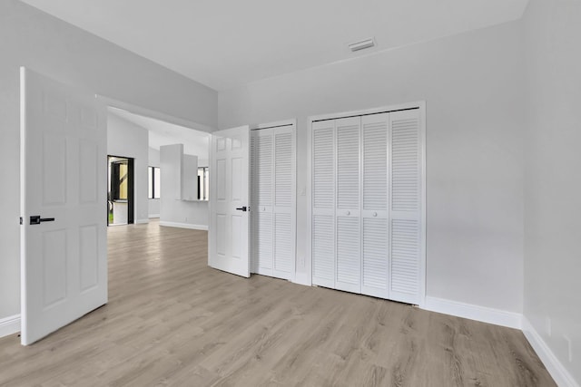 unfurnished bedroom featuring two closets and light wood-type flooring