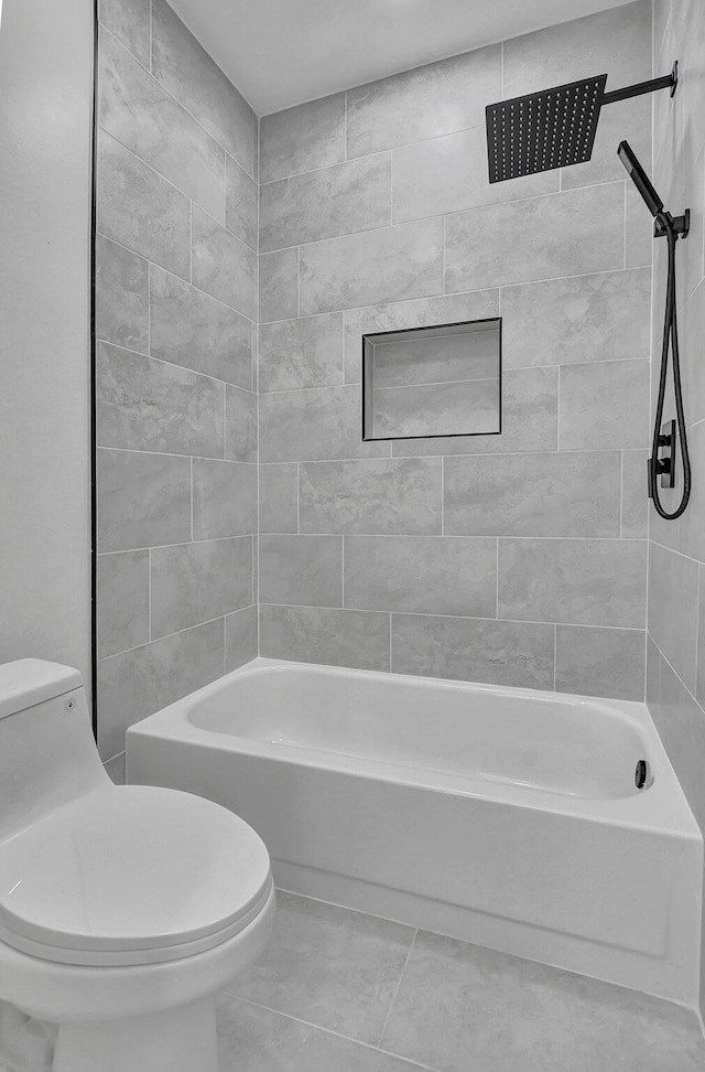 bathroom featuring tile patterned flooring, tiled shower / bath combo, and toilet