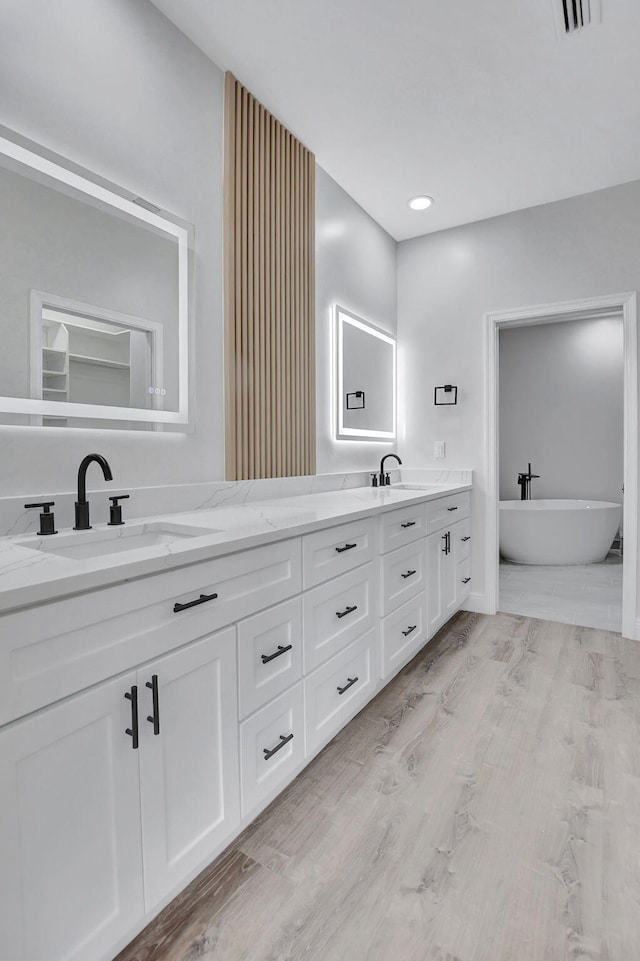 bathroom with a bathtub, vanity, and wood-type flooring