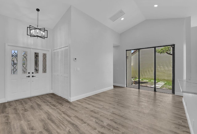 entrance foyer featuring high vaulted ceiling, light hardwood / wood-style floors, and a notable chandelier