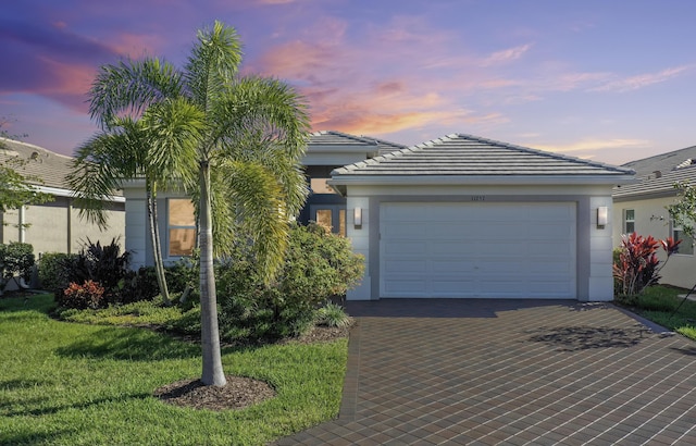 view of front of home with a garage and a lawn