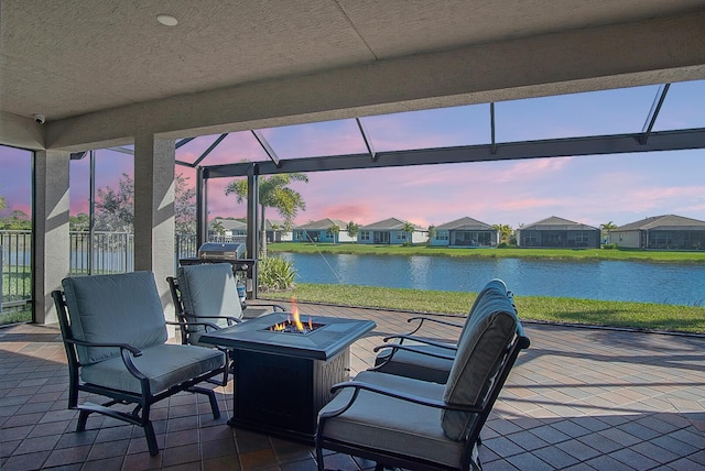 patio terrace at dusk with a water view and an outdoor fire pit