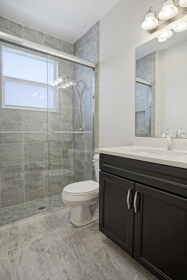 bathroom featuring vanity, toilet, and a shower with shower door