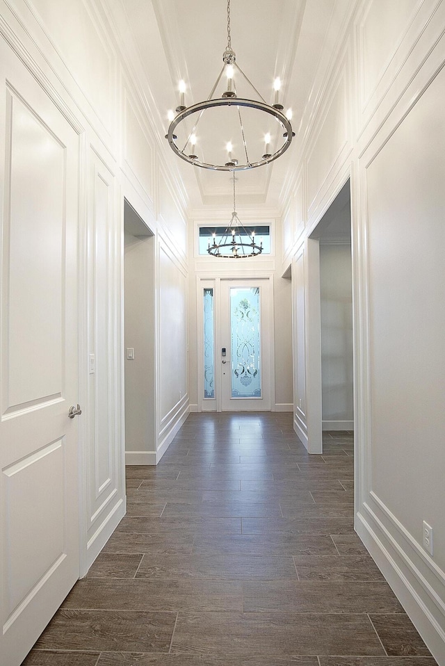 interior space featuring a raised ceiling, ornamental molding, dark hardwood / wood-style floors, and a notable chandelier