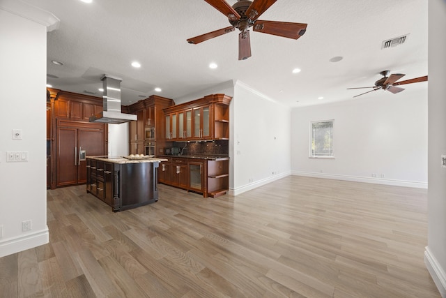 kitchen featuring a breakfast bar, a center island, light hardwood / wood-style flooring, backsplash, and island range hood