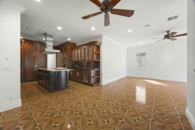 kitchen with built in appliances, tasteful backsplash, island range hood, ceiling fan, and a kitchen island