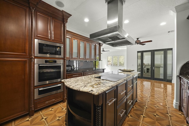 kitchen featuring french doors, a center island, island exhaust hood, dark stone counters, and appliances with stainless steel finishes