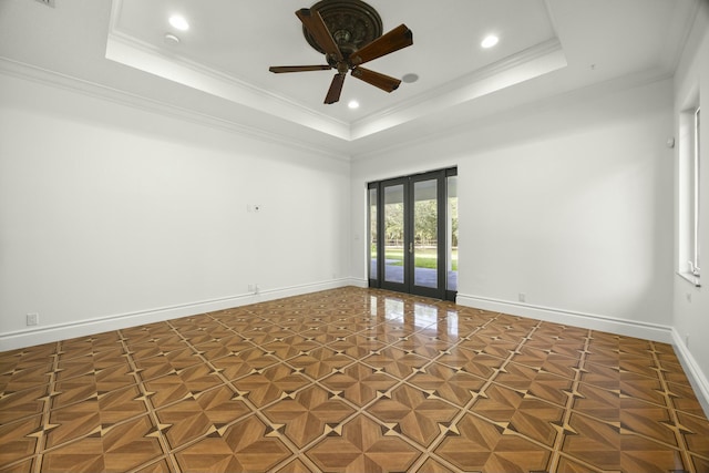 empty room with french doors, a tray ceiling, ceiling fan, and ornamental molding