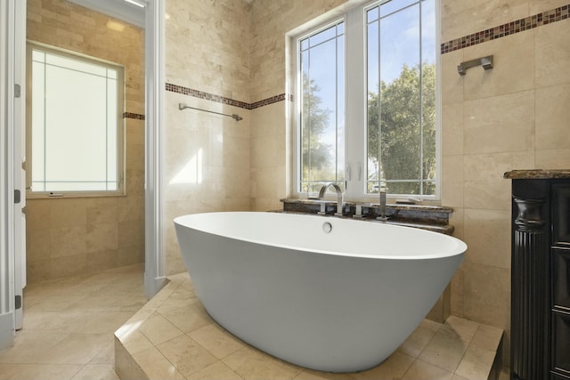 bathroom with tile patterned floors, plenty of natural light, tile walls, and a tub