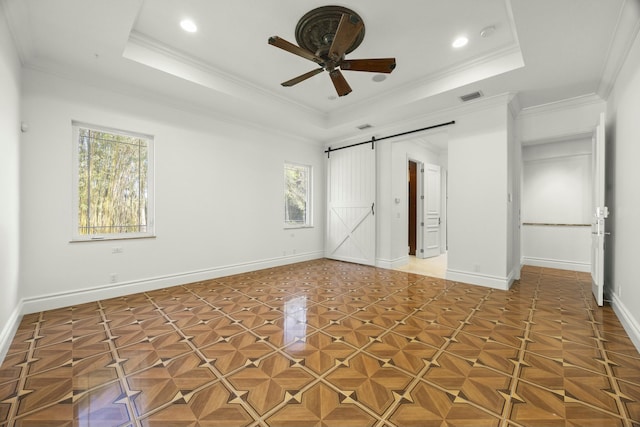 spare room featuring ceiling fan, a tray ceiling, a barn door, and ornamental molding