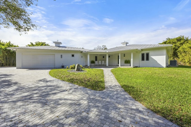 single story home with a garage, a porch, a front yard, and central AC unit