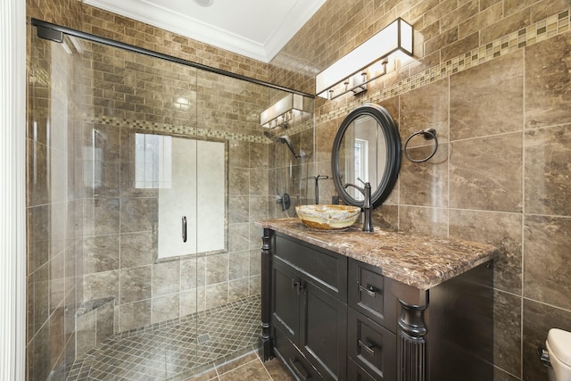 bathroom with a tile shower, vanity, crown molding, tile walls, and tile patterned flooring