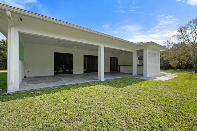 back of property with a yard and a patio