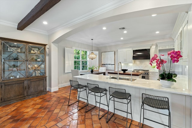 kitchen featuring custom exhaust hood, a kitchen bar, stainless steel appliances, tasteful backsplash, and pendant lighting