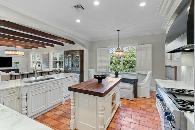 kitchen featuring a center island, sink, high end stainless steel range, white cabinets, and butcher block counters