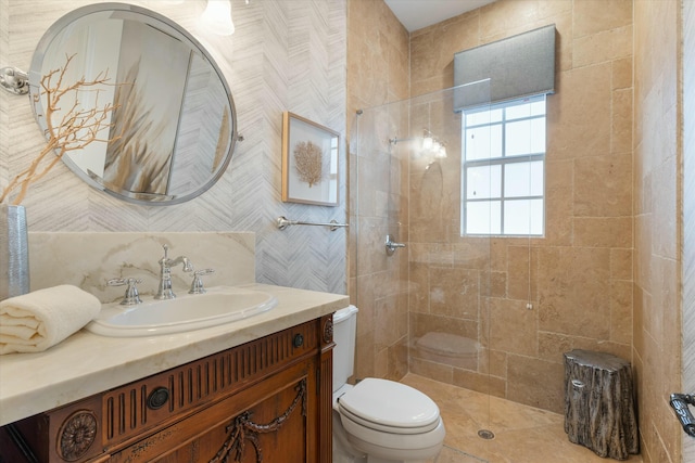 bathroom featuring toilet, tiled shower, and vanity