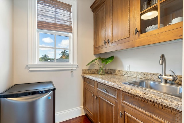 kitchen featuring light stone countertops, sink, and refrigerator