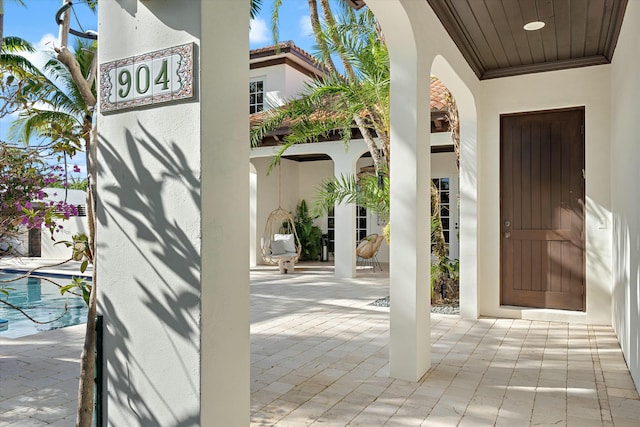 view of exterior entry featuring a swimming pool and a patio