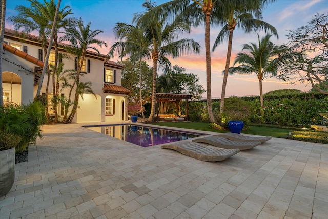 pool at dusk featuring a patio and a pergola