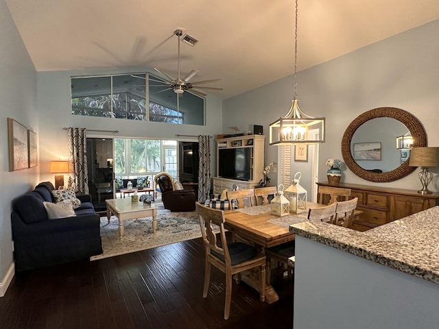 dining room featuring ceiling fan with notable chandelier, dark hardwood / wood-style flooring, and high vaulted ceiling