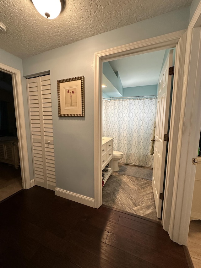 hallway with a textured ceiling and dark wood-type flooring