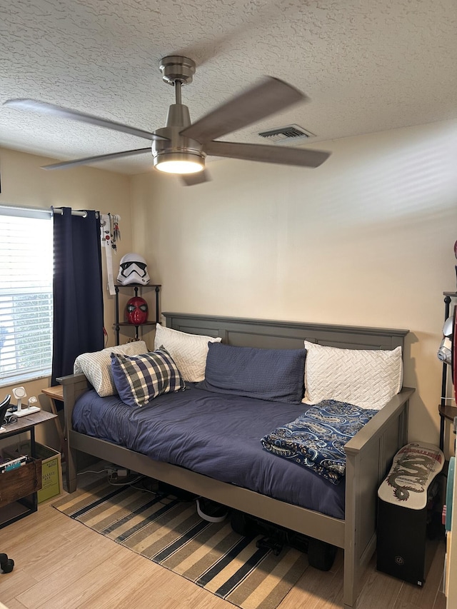 bedroom with a textured ceiling, hardwood / wood-style flooring, and ceiling fan