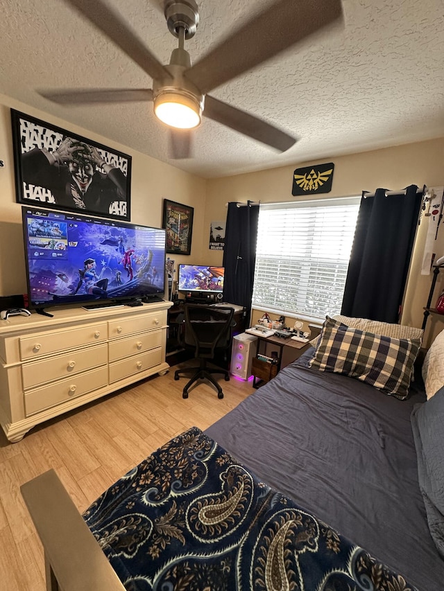 bedroom featuring ceiling fan, light wood-type flooring, and a textured ceiling