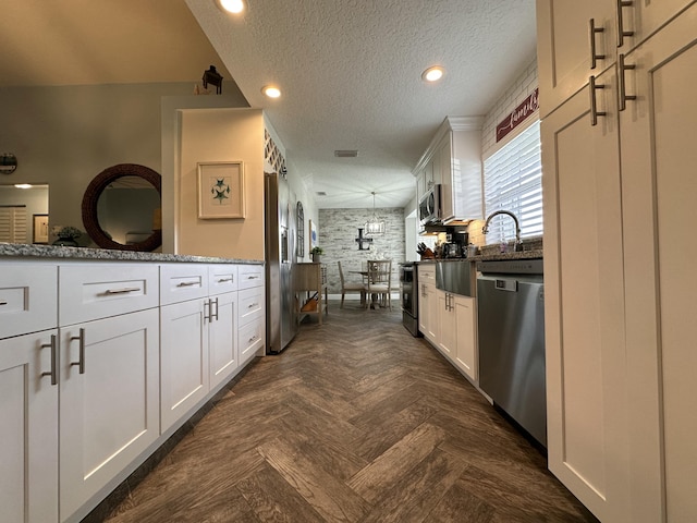 interior space featuring light stone counters, white cabinets, a textured ceiling, and appliances with stainless steel finishes