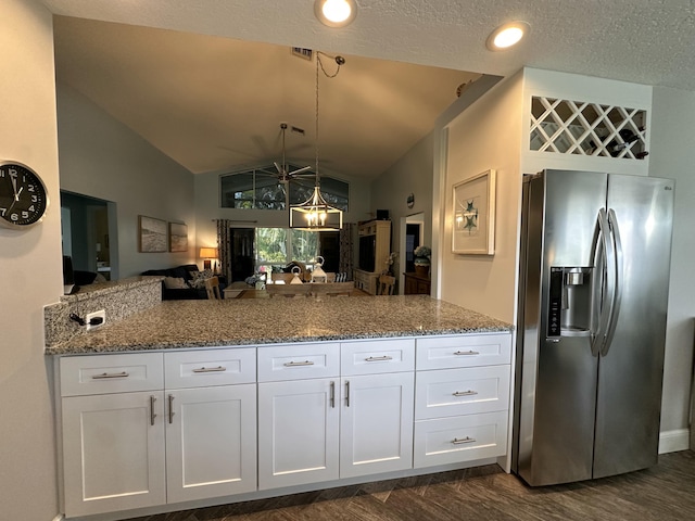 kitchen featuring lofted ceiling, white cabinets, stainless steel fridge, stone countertops, and kitchen peninsula