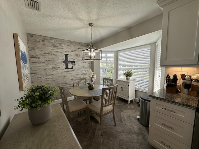 dining space featuring dark parquet flooring, a textured ceiling, and a notable chandelier