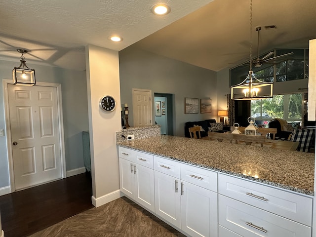 kitchen featuring white cabinets, kitchen peninsula, hanging light fixtures, and vaulted ceiling