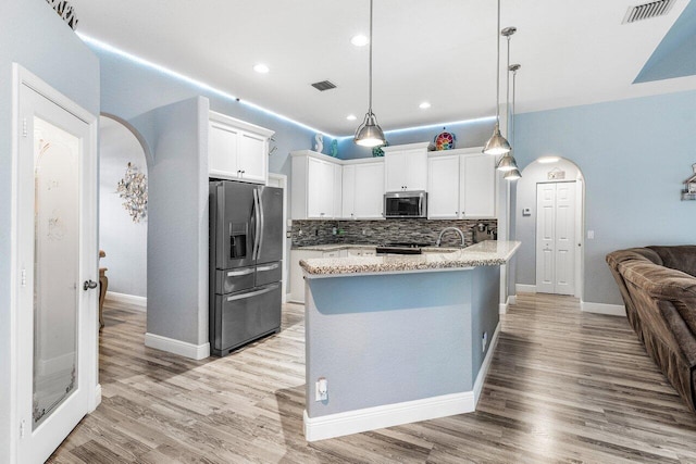 kitchen featuring hanging light fixtures, appliances with stainless steel finishes, a center island with sink, and white cabinets