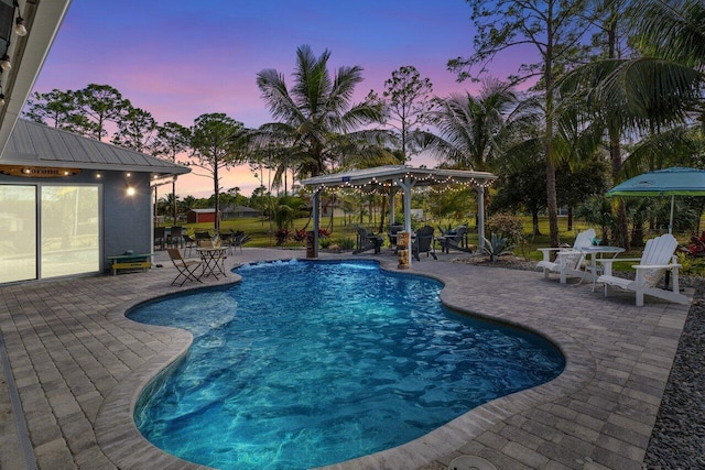 pool at dusk featuring a patio