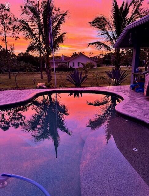 pool at dusk featuring a patio area