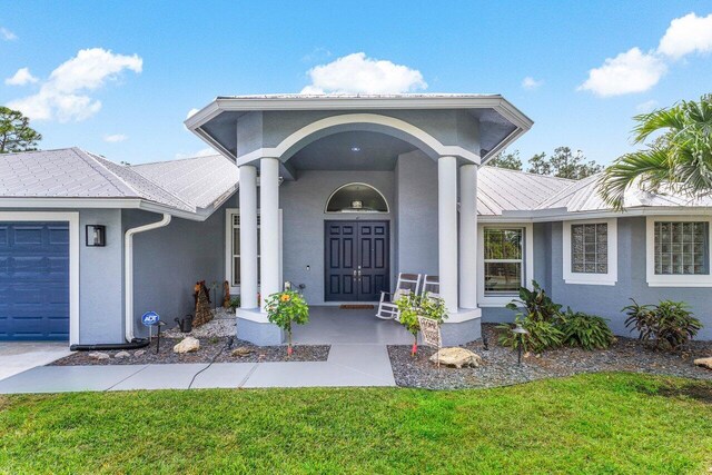 entrance to property featuring a garage and a lawn