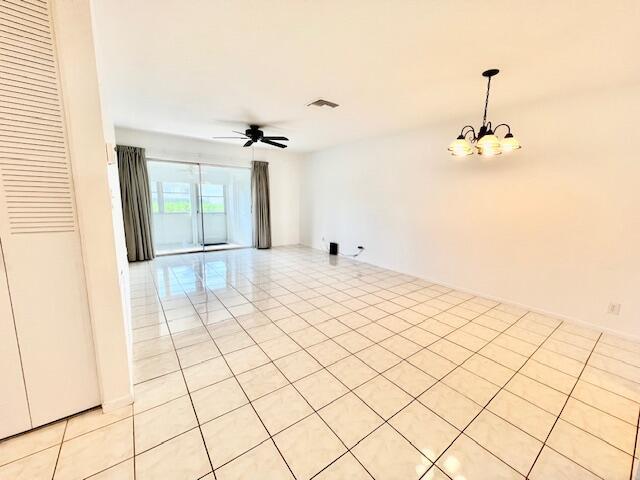 empty room featuring light tile patterned floors and ceiling fan with notable chandelier