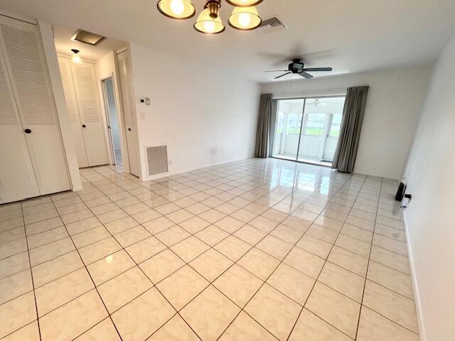 empty room featuring ceiling fan with notable chandelier and light tile patterned floors