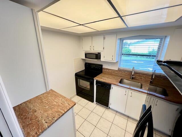 kitchen featuring sink, white cabinets, black appliances, and light tile patterned floors