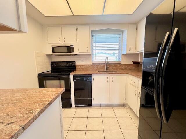 kitchen featuring sink, light tile patterned floors, white cabinets, and black appliances