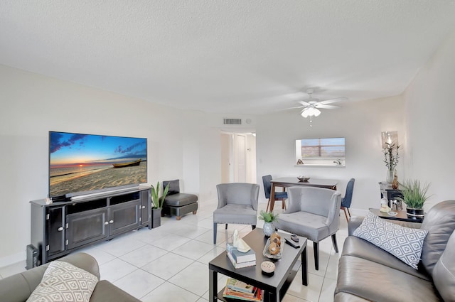 living room featuring ceiling fan, light tile patterned flooring, and a textured ceiling