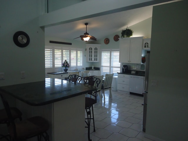 kitchen with kitchen peninsula, a breakfast bar, white dishwasher, vaulted ceiling, and white cabinetry