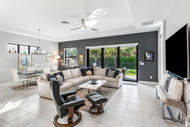 living room featuring ceiling fan with notable chandelier and a tray ceiling