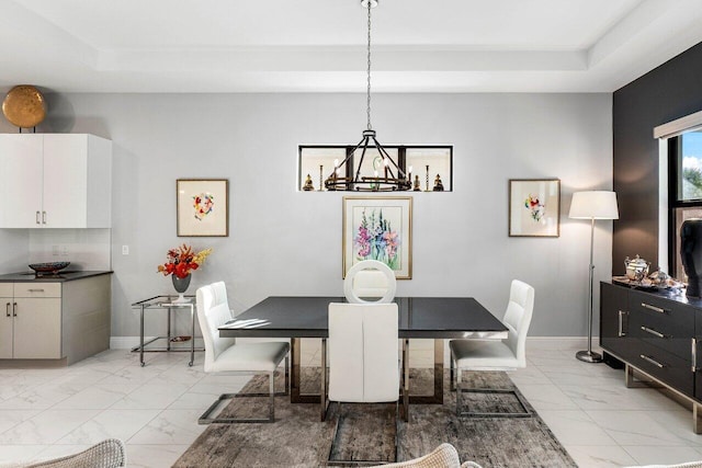 dining space featuring a raised ceiling and an inviting chandelier