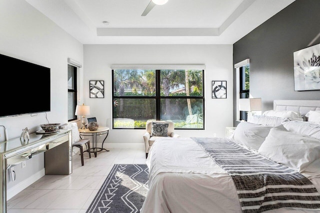 bedroom featuring a raised ceiling, multiple windows, and ceiling fan