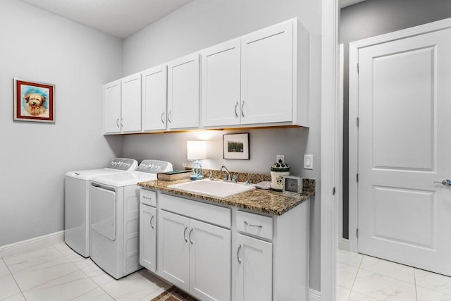 clothes washing area featuring washing machine and clothes dryer, sink, and cabinets