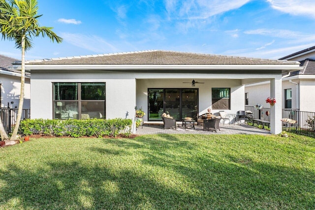 rear view of house with a lawn, ceiling fan, a patio, and a fire pit