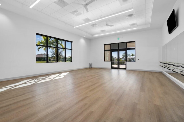 unfurnished living room featuring a tray ceiling, ceiling fan, plenty of natural light, and a high ceiling